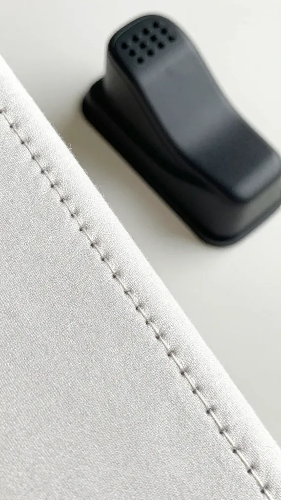 Closeup of a fabric edge with stitches and a calm sewing pedal in background